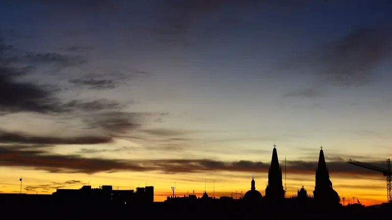 Siluetas de torres de iglesia y edificios contra el cielo naranja de un amanecer en Guadalajara