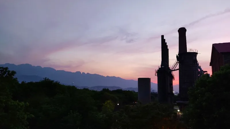 Antiguas estructuras de la fundidora y la Sierra Madre Oriental recortadas contra el cielo rosa del atardecer, vistas desde el Parque Fundidora de Monterrey