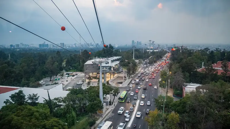 Cables de la Línea 3 del Cablebús sobre la avenida Constituyentes y el bosque de Chapultepec, con los edificios de la ciudad al fondo bajo un cielo nublado de tarde