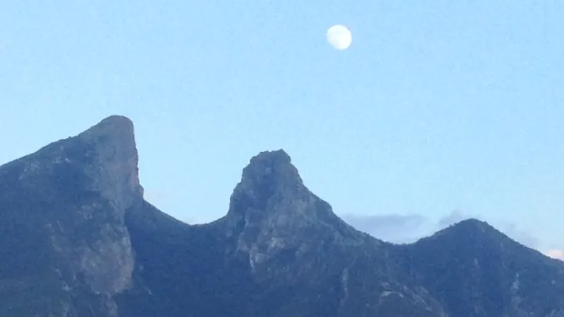 Los picos del Cerro de la Silla al atardecer, con la luna llena en el cielo