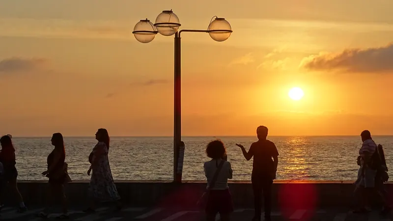 Siluetas de personas en el Malecón de Mazatlán mirando el sol bajar sobre el Pacífico