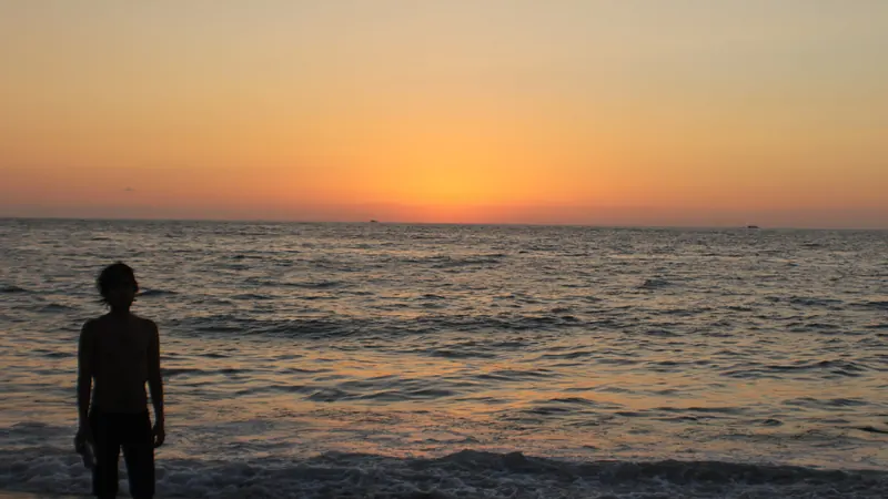 Silueta de una persona en la orilla de una playa de Puerto Vallarta con el cielo naranja después de la puesta de sol
