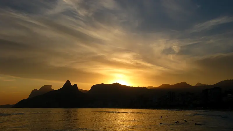 Sol se pondo atrás do Morro Dois Irmãos, visto do Arpoador, com o mar de Ipanema dourado